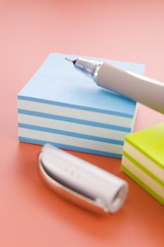 Piles of sticky notes and pen over a red table