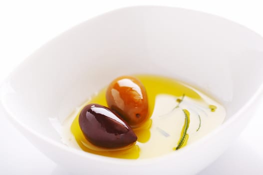 Two olives and olive oil on the white plate