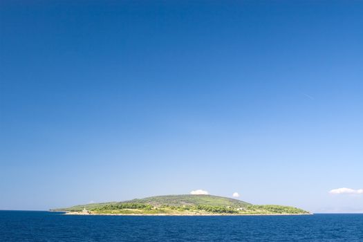 Lonely mediterranean green island against blue sky 