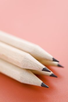 Pile of wooden pencils pver a light red background