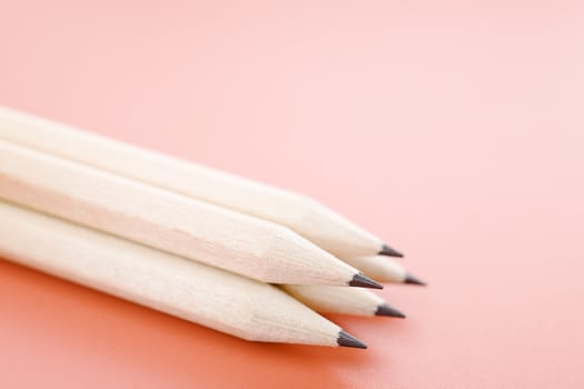 Pile of wooden pencils over a light red background