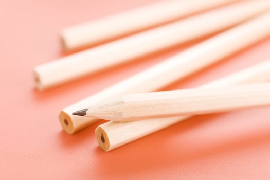 Pile of wooden pencils over a light red background
