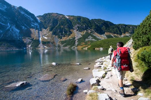 Couple trekking by the side of mountain pond in Tatra Mountains, Poland