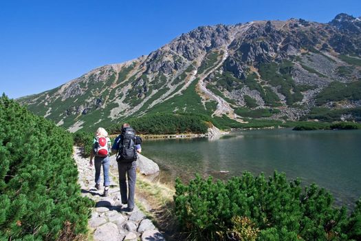 Couple trekking by the side of mountain pond in Tatra Mountains, Poland