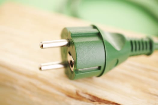 Green energy concept (green energy plug on the wood)