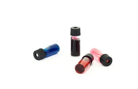 Vials with colored liquid on white background