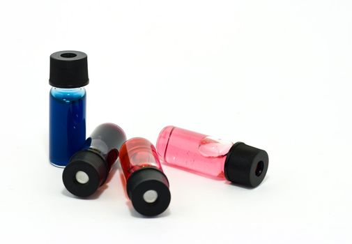 Vials with colored liquid on white background
