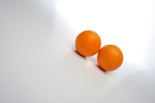 A pair of juicy oranges, side by side over a white background, big space for text and design elements. Look at my gallery for more fruits and vegetables