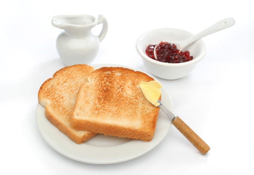 Two toast on a plate with butter on a knife and red jam behind. Deliciuos food for breakfast.  Look at my gallery for more meals