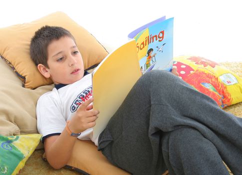 Boy in a room reading a book over a carpet. He looks interested and concentrated. Visit my gallery for more images of children
