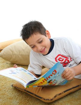 Boy in a room reading a book over a carpet. He is smiling and looks amused. Visit my gallery for more images of children
