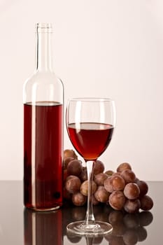 a bottle, a glass of wine and red grapes