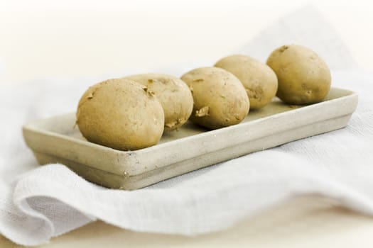 five raw potatoes on the vase on the table