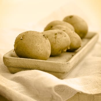 five raw potatoes on the vase on the table