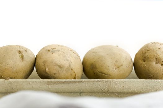 five raw potatoes on the vase on the table