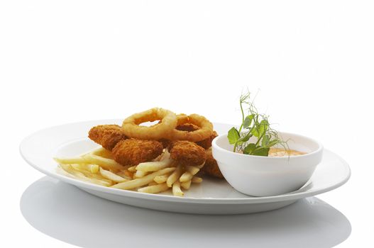 Nuggets, french fries and fried onion rings on the plate