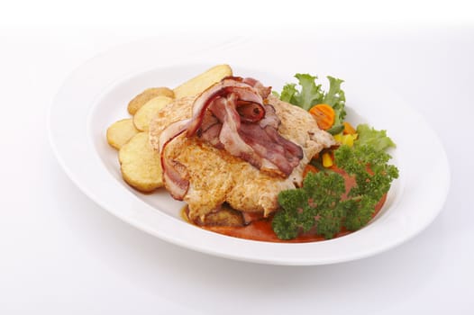 Pork meat with bacon and deep fried potatoes over a white background