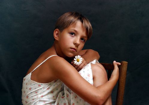 The girl sitting on a chair on a dark background