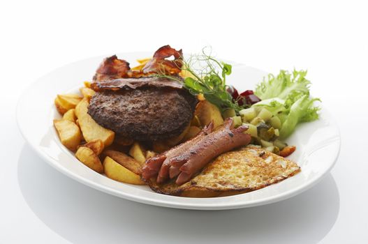 Deep fried potatoes, sausages, beef, bacon and vegetables on dinner plate