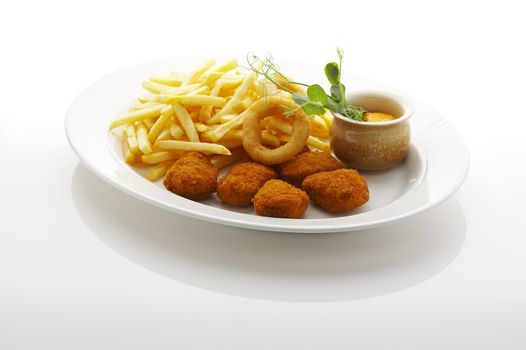 Nuggets, french fries and fried onion rings on the plate