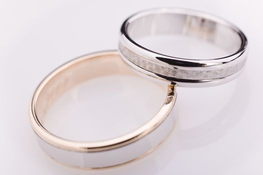 Two white gold engagement rings over a white reflective background