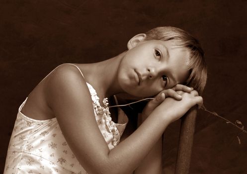 The girl sitting on a chair with a camomile on a dark background