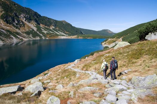 Couple trekking by the side of mountain pond in Tatra Mountains, Poland