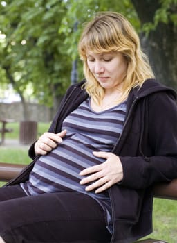 Beautiful pregnant woman enjoying summer sunny day at park