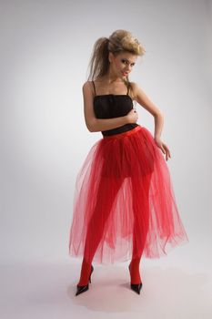 Beautiful woman in red diaphanous skirt on grey background