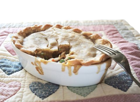 a chicken potpie in an individual casserole dish on a quilted place mat with calico hearts