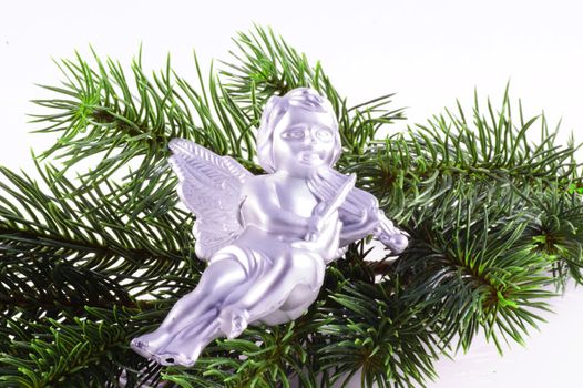 Silver colored angel on a christmas tree branch, isolated on white.