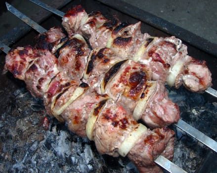 Fried slices of meat and onions on skewers