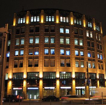 Night city: the modern building shined with fires, drive passing cars