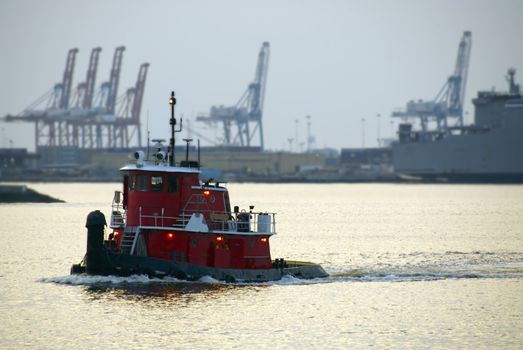 A red tugboat cruises the waterways at dusk