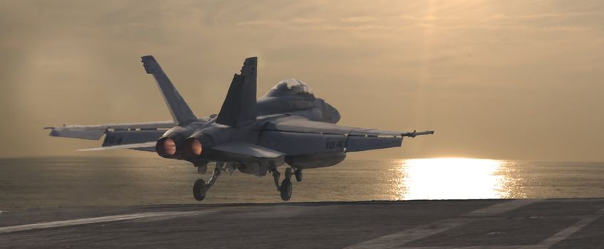 An F-18 Super Hornet is launched from a nuclear powered aircraft carrier at sunset