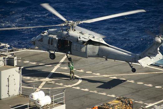 A Navy Helicopter delivers a package to a ship