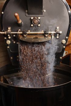 The freshly roasted coffee beans from a large coffee roaster being poured into the cooling cylinder.  Motion blur on the beans.