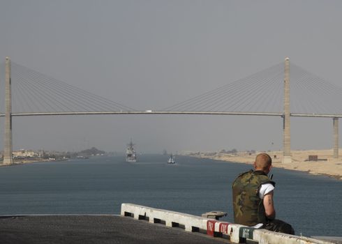A soldier stands guard while his ship passes through the Suez Canal