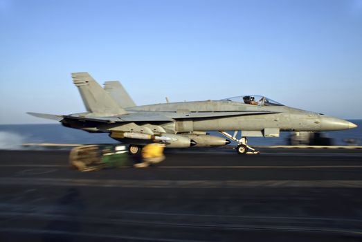 An F-18 Hornet rockets down the deck of an aircraft carrier