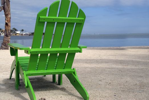 A lone neon green beach chair breaks the monotony of a natural toned beach