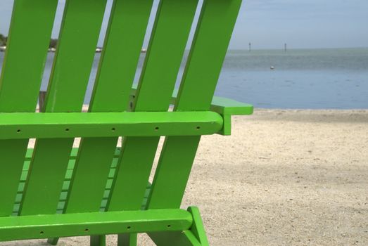 A bright green beach chair sits on a warm, tropical beach