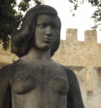 A medieval female statue adorns the grounds outside of a Portuguese castle