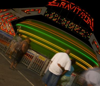 An African American couple stand in line and wait for their turn on a spinning carnival ride at night