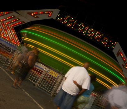 An African American couple stand in line and wait for their turn on a spinning carnival ride at night