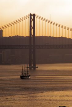 A Clipper ship passes underneath a beautiful suspension bridge