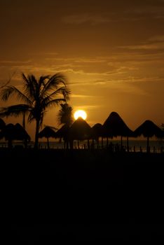 a tropical village of huts and cabanas at sunset