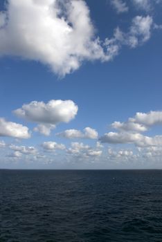 Puffy white clouds fill the sky over calm blue ocean waters