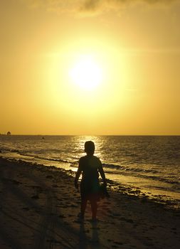 A small child admires the beauty of a wonderful beach sunset