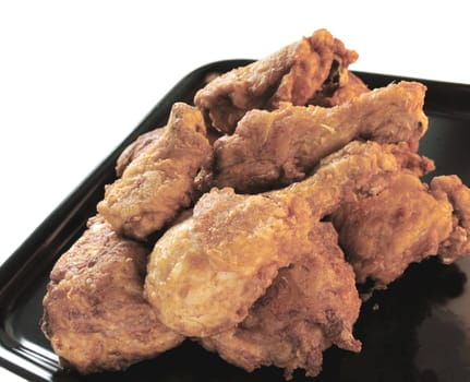 golden fried chicken on a black tray isolated on white