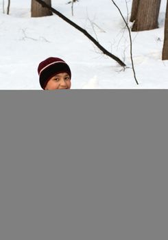 happy boy on snow with snowball in the winter forest